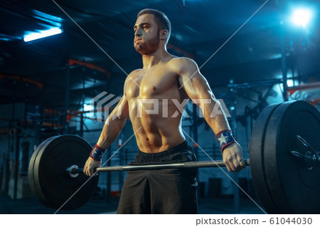 Caucasian man practicing in weightlifting in gym 61044030