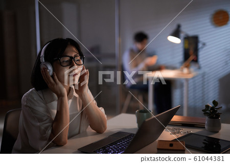 Businesswoman using headphones in her work Businesswoman using headphones in her work 61044381