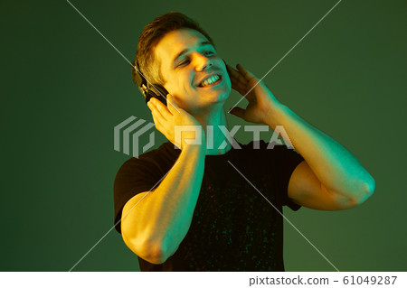 Caucasian man's portrait isolated on green studio background in neon light Caucasian man's portrait isolated on green studio background in neon light 61049287