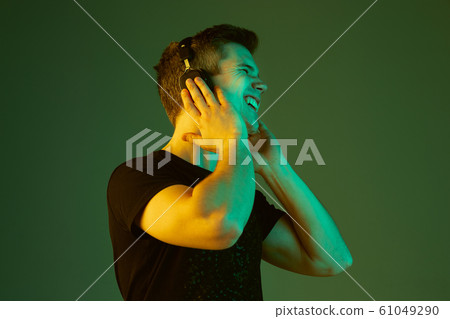 Caucasian man's portrait isolated on green studio background in neon light 61049290