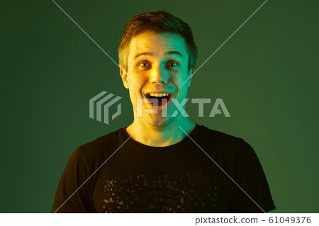 Caucasian man's portrait isolated on green studio background in neon light Caucasian man's portrait isolated on green studio background in neon light 61049376