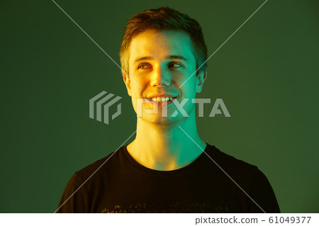 Caucasian man's portrait isolated on green studio background in neon light 61049377