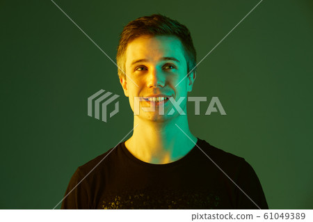 Caucasian man's portrait isolated on green studio background in neon light 61049389