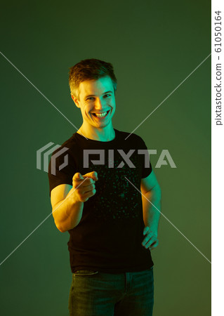 Caucasian man's portrait isolated on green studio background in neon light 61050164
