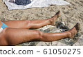 tanned wet female legs on the beach 61050275