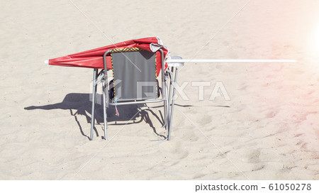 red sun umbrella on a chair on the beach 61050278