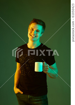 Caucasian man's portrait isolated on green studio background in neon light 61050423