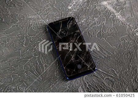 Broken glass screen smartphone in hand of upset girl, white background 61050425