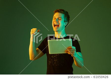 Caucasian man's portrait isolated on green studio background in neon light 61050426