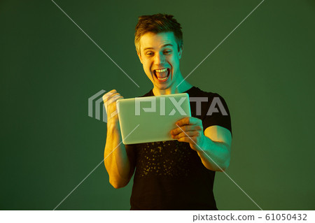 Caucasian man's portrait isolated on green studio background in neon light 61050432