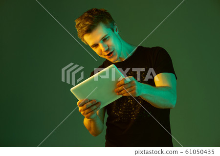 Caucasian man's portrait isolated on green studio background in neon light 61050435