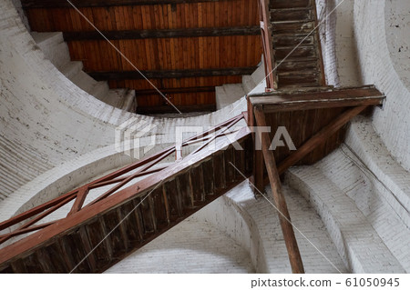 Old decrepit wooden staircase leading up inside of the building 61050945