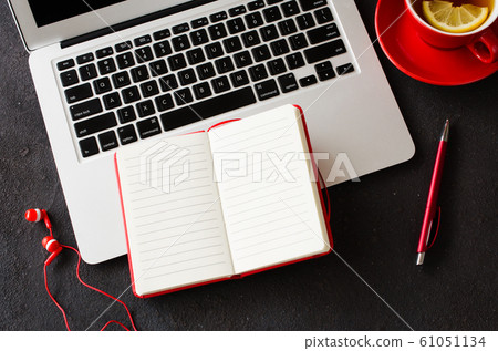 Blank red notebook with pen, computer laptop, headphones and cup of tea on dark table. Blank red notebook with pen, computer laptop, headphones and cup of tea on dark table. 61051134
