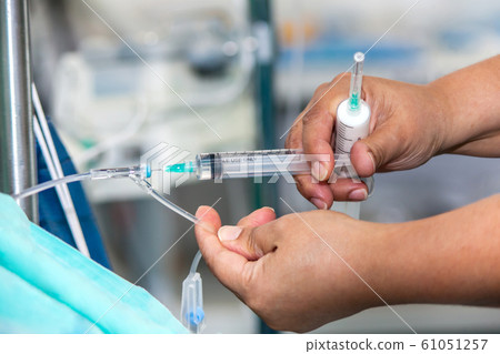Nurse injecting a drug through an infusion system 61051257