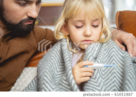 Father and daughter looking at digital thermometer Father and daughter looking at digital thermometer 61051987
