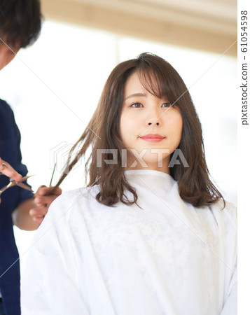A woman cutting her hair in a hair salon 61054598