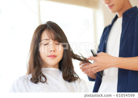 A woman cutting her hair in a hair salon 61054599