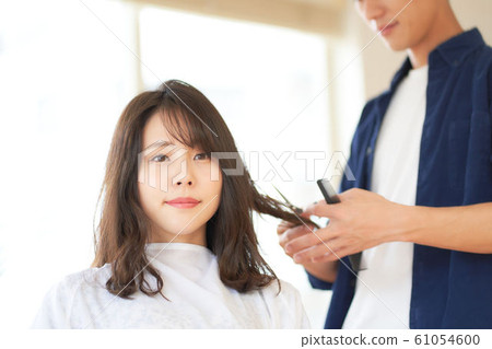 A woman cutting her hair in a hair salon 61054600