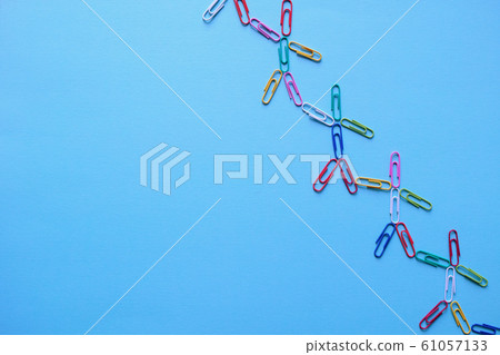 A person pulling a foot shaped like a colorful paper clip on the top right of a blue construction paper A person pulling a foot shaped like a colorful paper clip on the top right of a blue construction paper 61057133