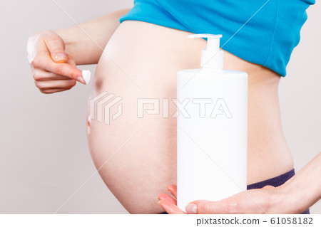 Pregnant woman applying moisturizing lotion 61058182