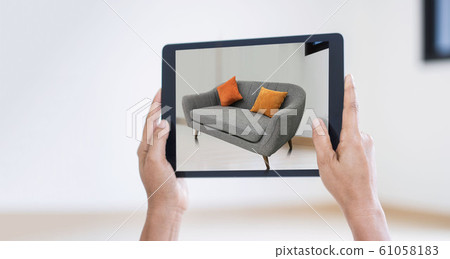 AR augmented reality. Hand holding digital tablet, AR application, simulate sofa furniture and and interior design  real room background, modern technology. 61058183
