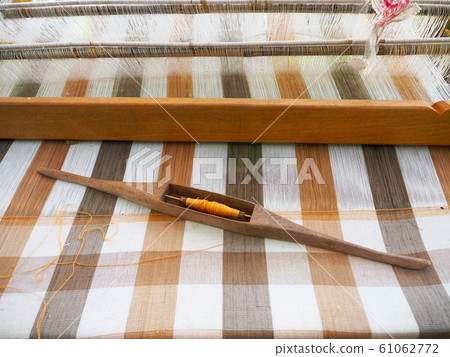 Thai style traditional hand-woven cotton the device consists of loom and weaving shuttle. Thai style traditional hand-woven cotton the device consists of loom and weaving shuttle. 61062772