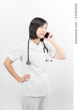 Young asian nurse with a stethoscope talking on the phone, isolated over white background. 61064958