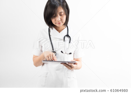 Young asian nurse with a stethoscope using a digital tablet, isolated over white background. 61064980