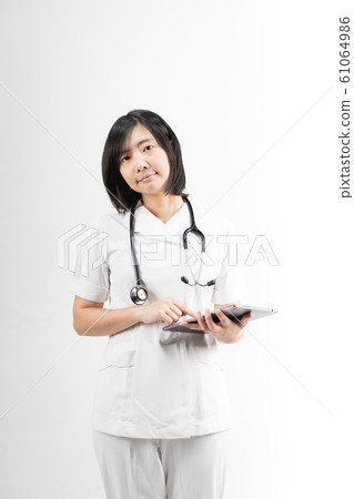 Young asian nurse with a stethoscope using a digital tablet, isolated over white background. Young asian nurse with a stethoscope using a digital tablet, isolated over white background. 61064986