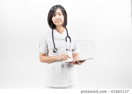 Young asian nurse with a stethoscope using a digital tablet, isolated over white background. Young asian nurse with a stethoscope using a digital tablet, isolated over white background. 61065137