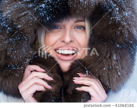 Close up portrait of a happy woman in fur hood looking at camera. Close up portrait of a happy woman in fur hood looking at camera. 61068188