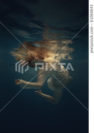Girl in a beautiful dress swims underwater 61068643