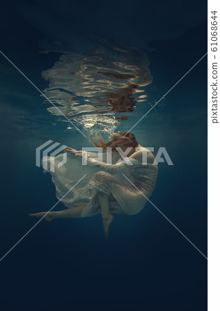 Girl in a beautiful dress swims underwater 61068644