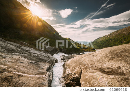 Kinsarvik, Hordaland, Norway. Water Stream Through Rocks In Hardangervidda Mountain Plateau. Sun Sunshine Above Rocky Landscape In Summer Sunny Day. Famous Norwegian Landmark And Popular Destination Kinsarvik, Hordaland, Norway. Water Stream Through Rocks In Hardangervidda Mountain Plateau. Sun Sunshine Above Rocky Landscape In Summer Sunny Day. Famous Norwegian Landmark And Popular Destination 61069618