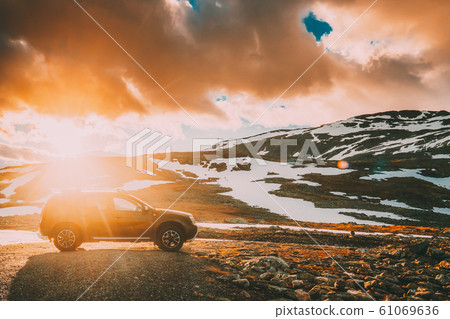 Aurlandsfjellet, Norway. Car SUV Parked Near Aurlandsfjellet Scenic Route Road In Summer Norwegian Landscape. Popular Destination In Sunset Lights Aurlandsfjellet, Norway. Car SUV Parked Near Aurlandsfjellet Scenic Route Road In Summer Norwegian Landscape. Popular Destination In Sunset Lights 61069636