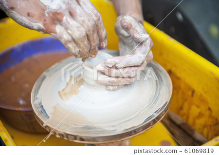 The potter makes pottery dishes on potter's wheel. The potter makes pottery dishes on potter's wheel. 61069819