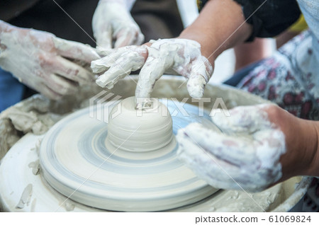 The potter makes pottery dishes on potter's wheel. The potter makes pottery dishes on potter's wheel. 61069824