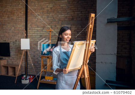 Nice young woman looking at the canvas 61070402