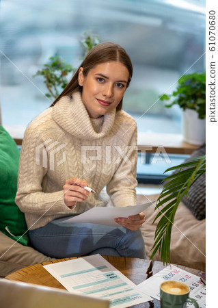 Smiling woman working with papers in a cafe 61070680