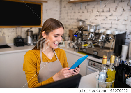 Smiling cafe employee using the tablet for her work Smiling cafe employee using the tablet for her work 61070902