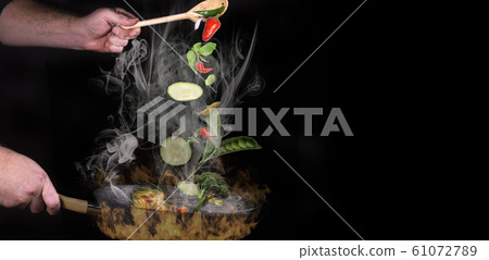 Chef roasts vegetables in a pan and stirred with a wooden spoon Chef roasts vegetables in a pan and stirred with a wooden spoon 61072789