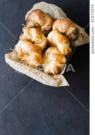 Baked fresh fragrant buns. Traditional homemade pastries. Pigtail buns top view. Baked fresh fragrant buns. Traditional homemade pastries. Pigtail buns top view. 61073074