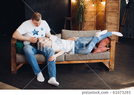 Young couple laying together on belly in bed at Young couple laying together on belly in bed at 61073265