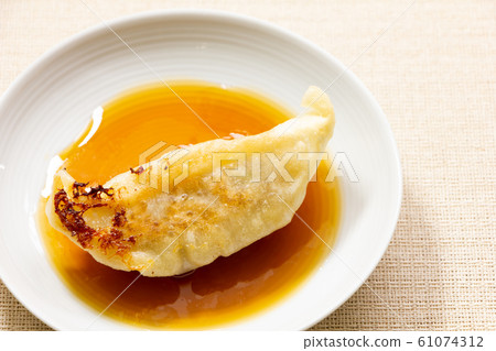 Fried gyoza put in a small plate with dumpling sauce. Fried gyoza put in a small plate with dumpling sauce. 61074312