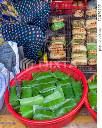 Grilled sticky rice wrapped with banana leaves at Cambodian market 61076205