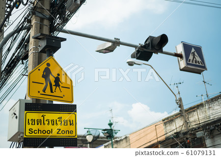 Yellow school zone warning sign at the roadside 61079131