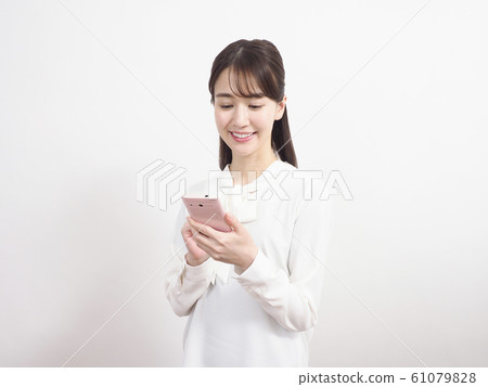 Smiling woman looking at pink smartphone 61079828