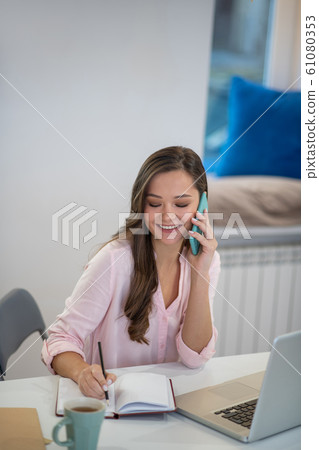 Delighted young businesswoman talking on the phone 61080353