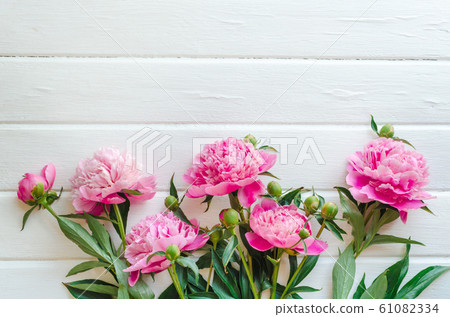 Pink peony flowers on white wooden table. womans day or wedding background. Top view. Pink peony flowers on white wooden table. womans day or wedding background. Top view. 61082334