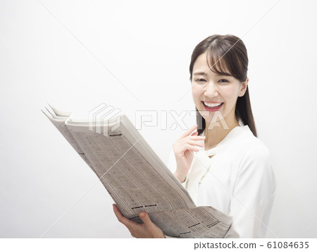 Business woman smiling looking at stock column in newspaper 61084635